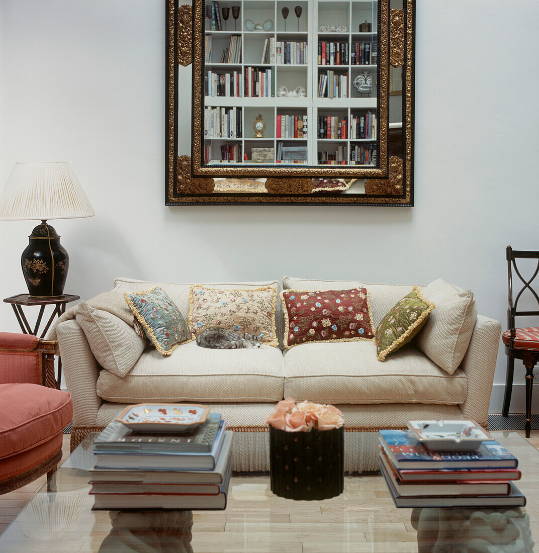 Modernes Wohnzimmer im Landhausstil mit Sofa, Couchtisch aus Glas und großem Spiegel mit offenem Regal