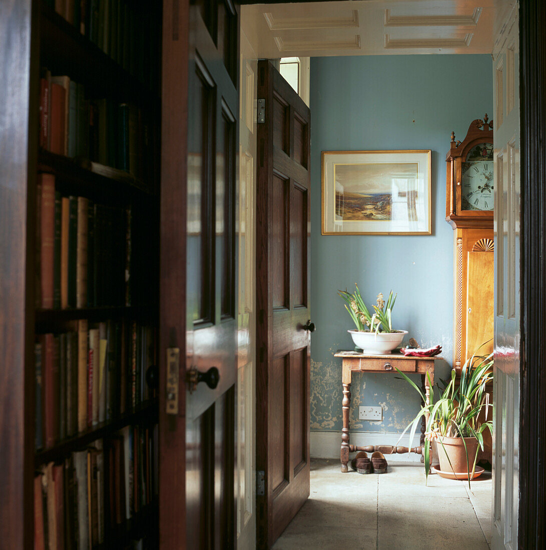 Blick auf die Eingangshalle mit Standuhr von der mit Büchern gefüllten Bibliothek aus