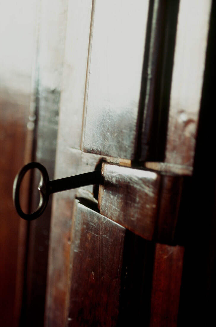 Old key in dark wooden door