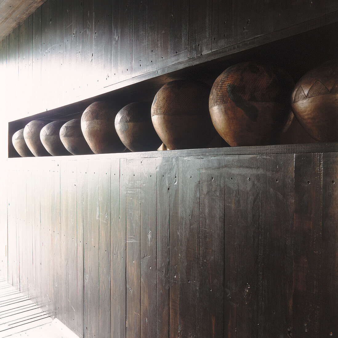 Wood panelled hallway with African pots embedded in the wall