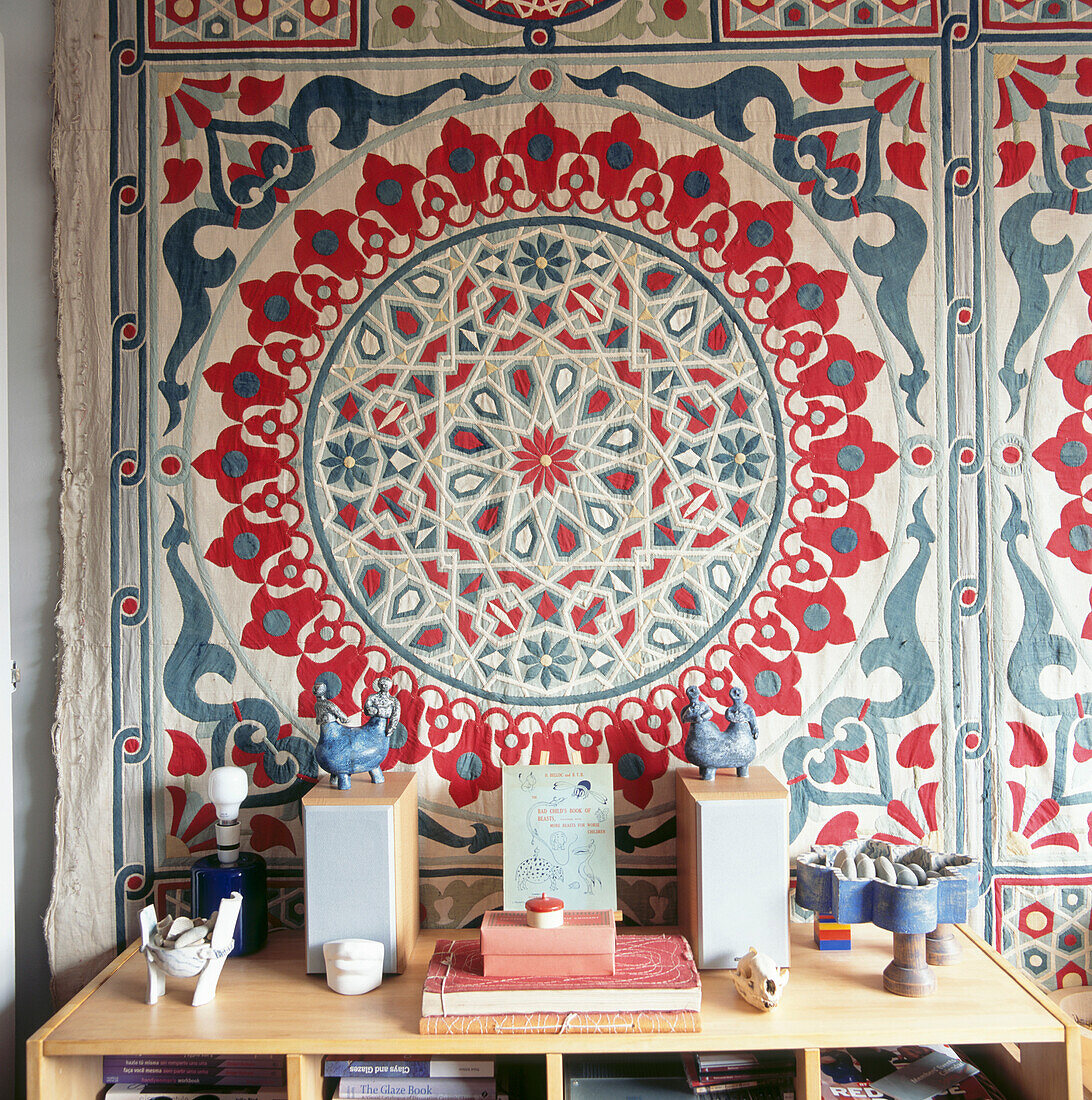 Close up of ethnic quilted wall hanging behind wooden cabinet with stereo unit 