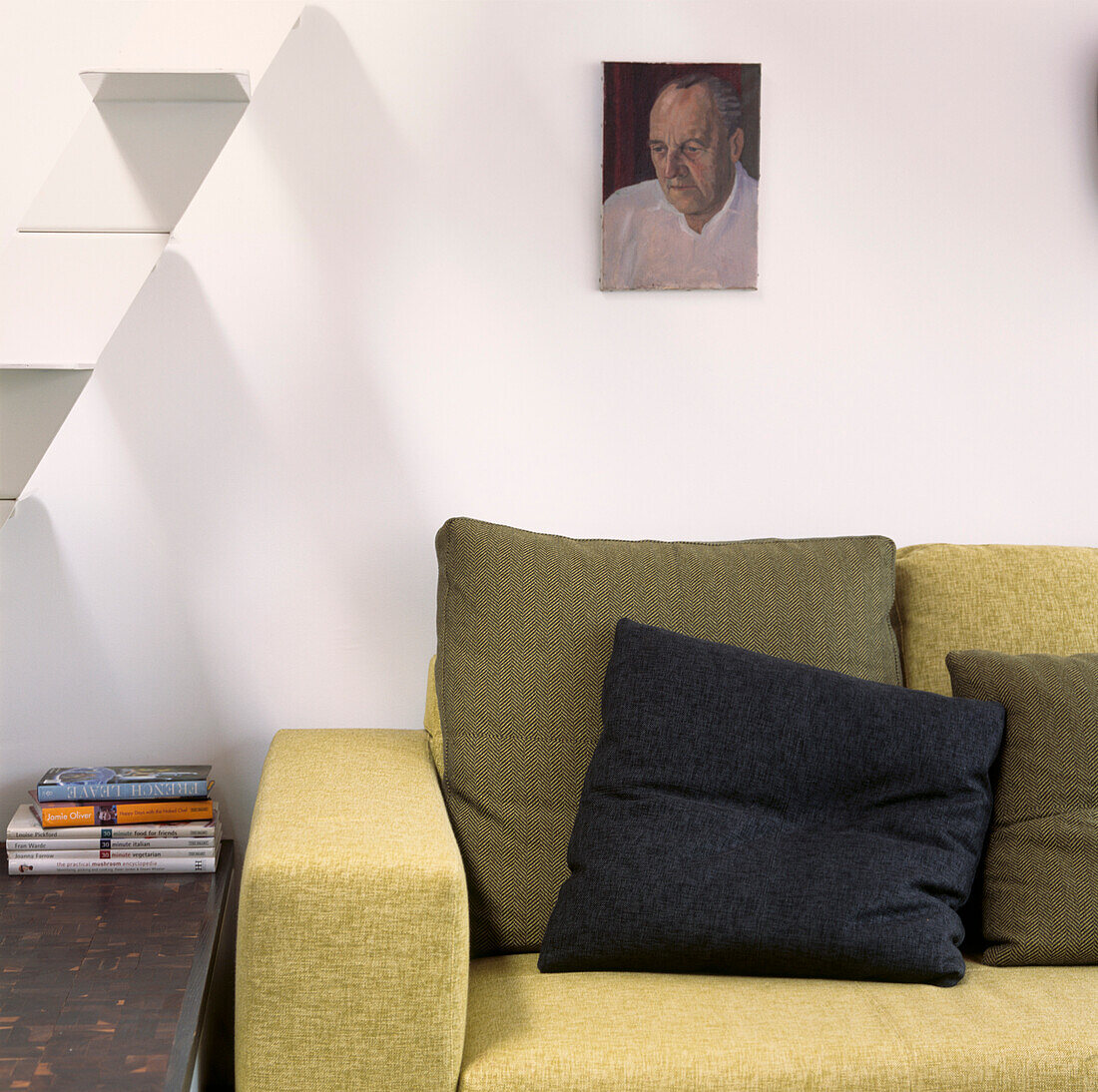 Nahaufnahme des blassgrünen italienischen Sofas neben einer minimalistischen Treppe aus weißem Metall im unteren Wohnbereich