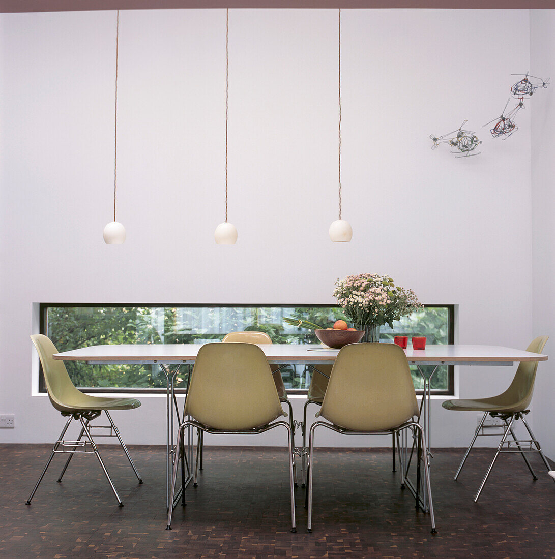 Original fibreglass shell Eames chairs around white rectangular table in modern dining room