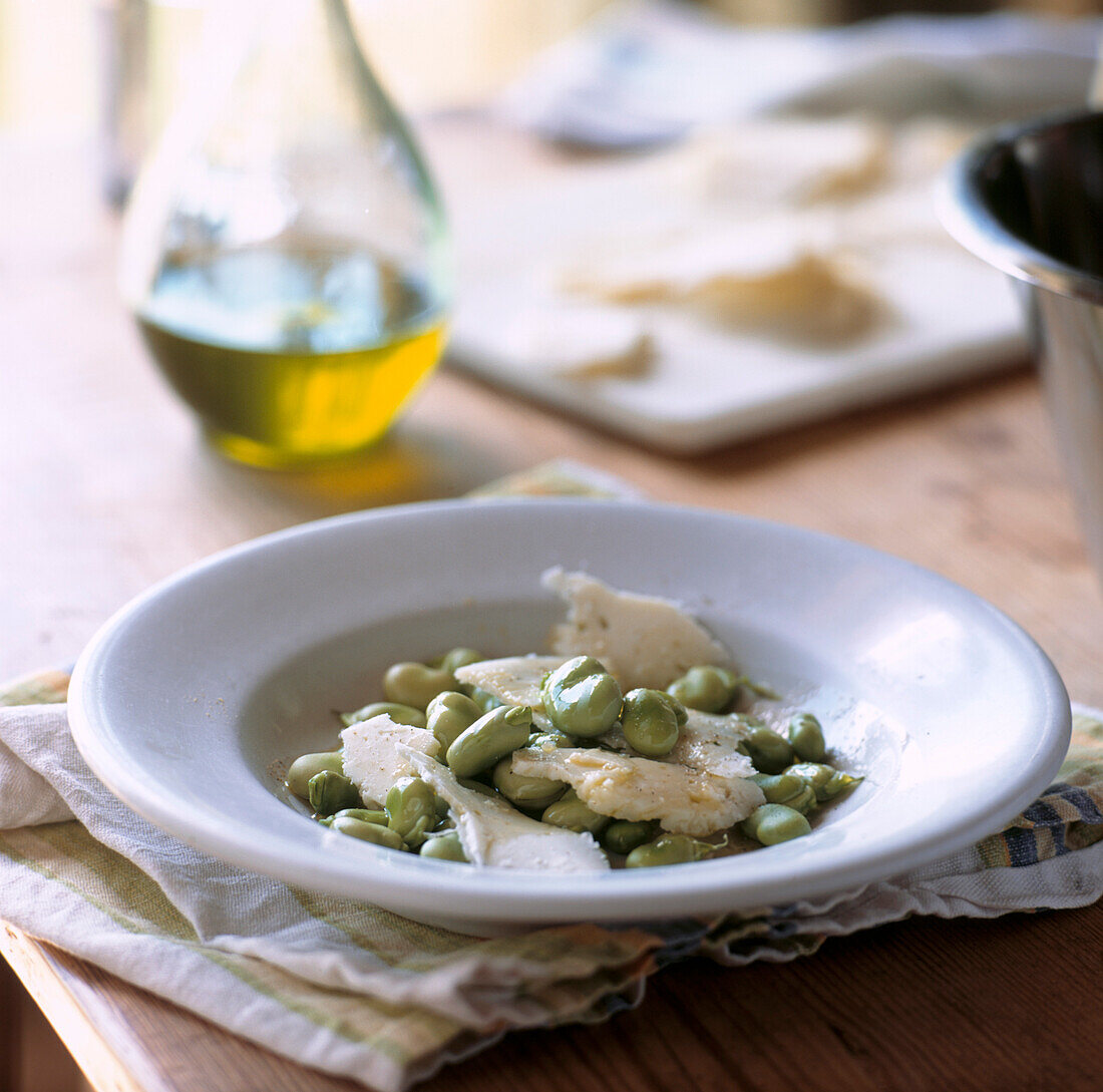 Broad bean and pecorino cheese salad on a table with dressing 