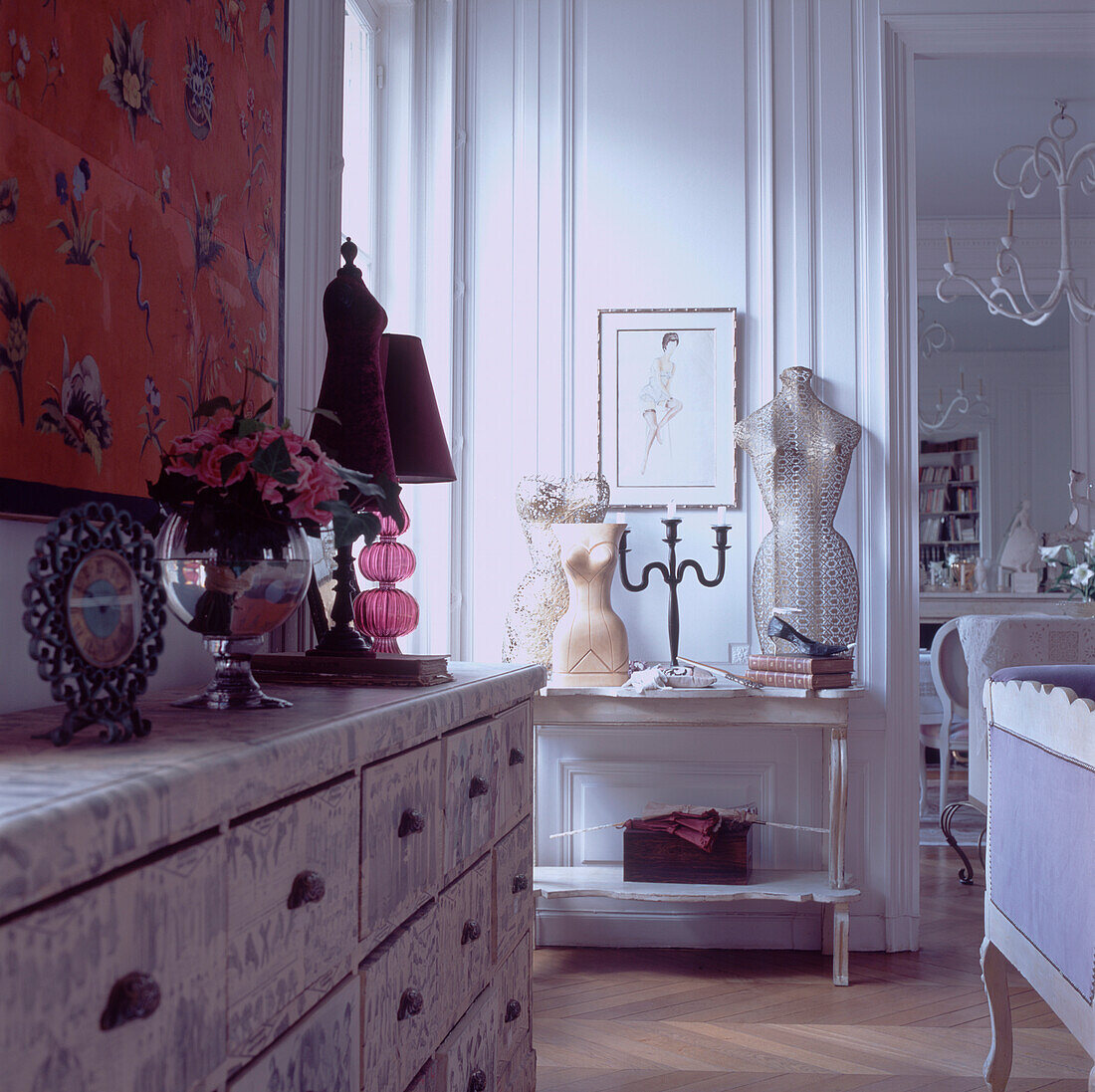 Elegantes Wohnzimmer mit ausgestellten Sammlerstücken auf einem Beistelltisch und einer mit Decoupage-Papier überzogenen Kommode