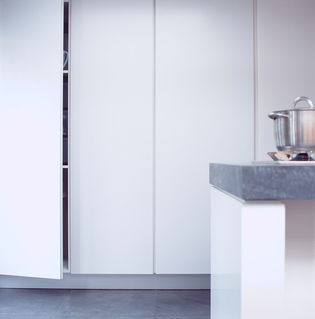 Aufbewahrungslösungen in einer modernen weißen Küche mit Schieferfliesenboden