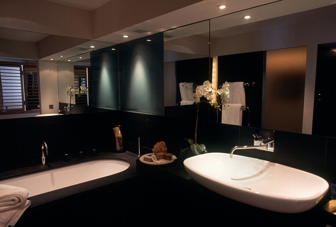 Black bathroom with mirrored wall and large basin