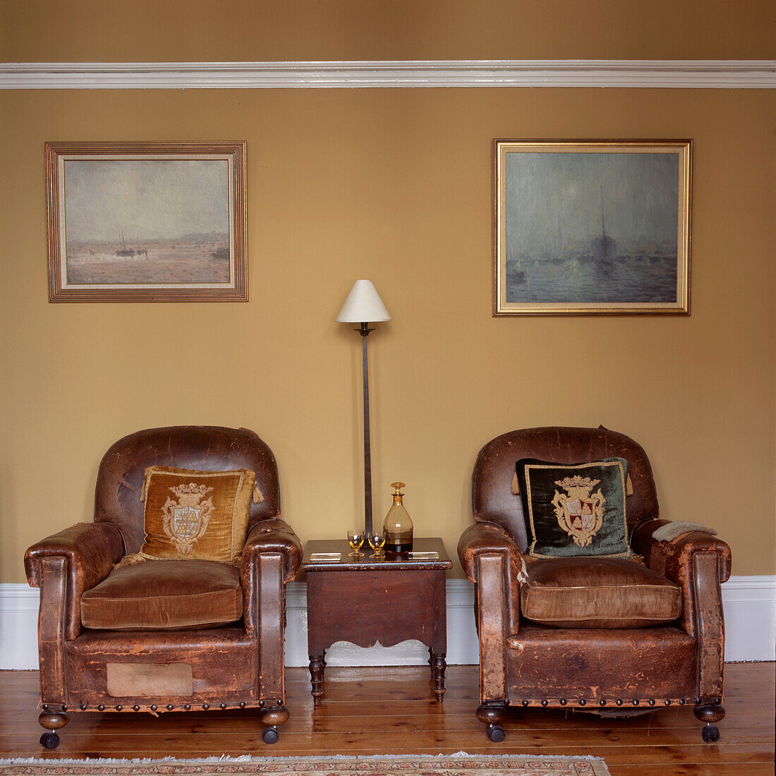 Zwei abgenutzte Vintage-Ledersessel in einem Wohnzimmer mit gelb gestrichenen Wänden