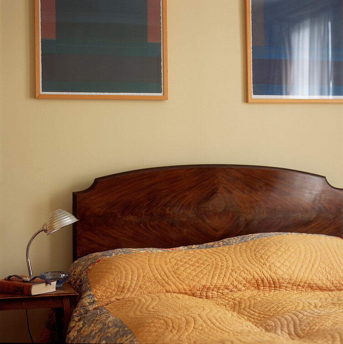 Schlafzimmer mit Kopfteil aus Mahagoniholz mit gelber Steppdecke