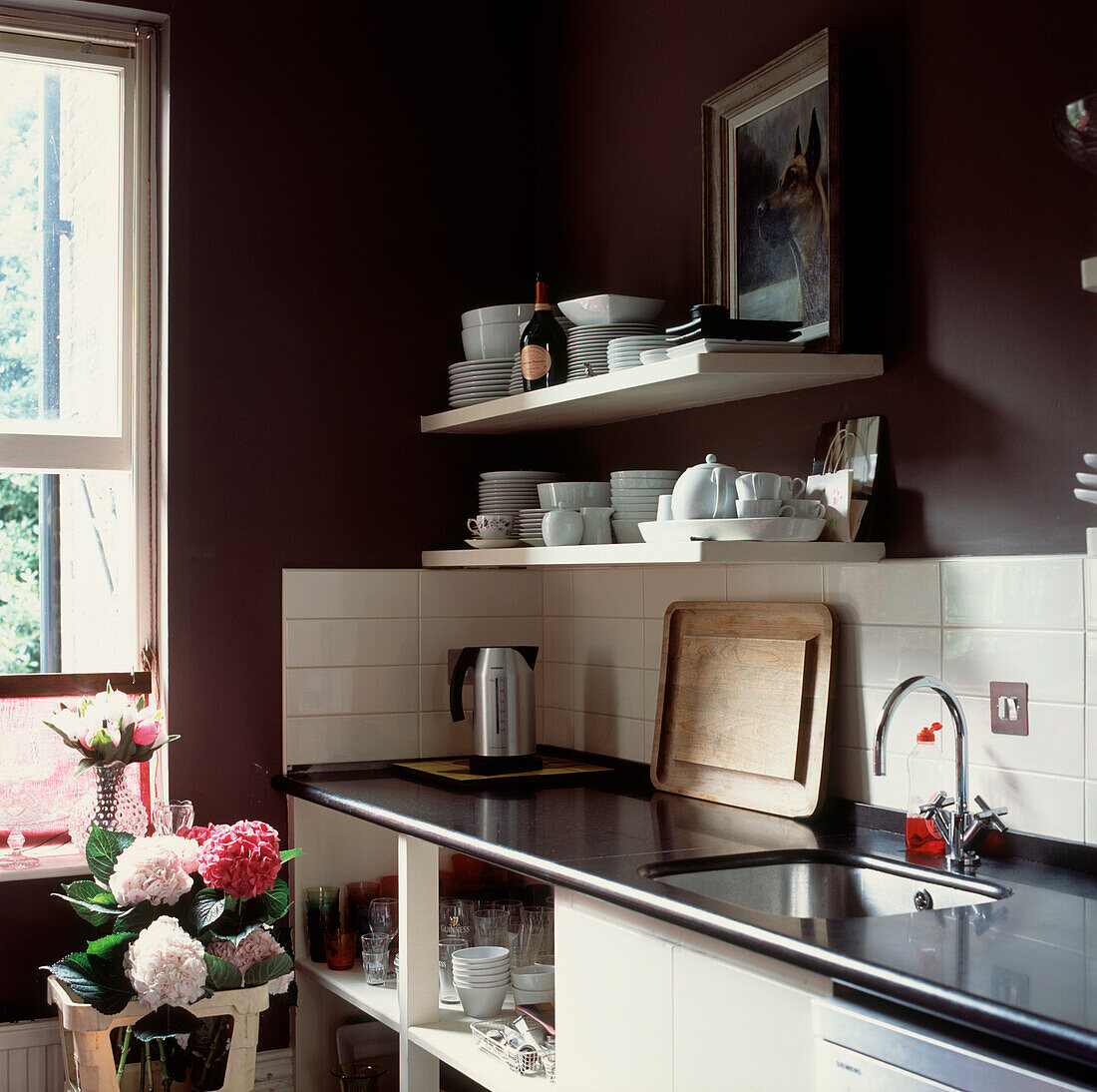 Detail der Küchenspüle und der Arbeitsplatten aus schwarzem Granit mit offenen Stauraumlösungen