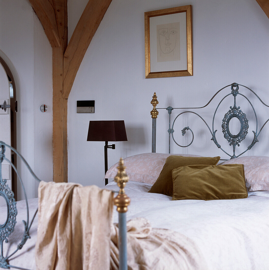 Modernes Schlafzimmer im Landhausstil mit verschnörkeltem gusseisernem Doppelbett mit Bettzeug und Kissen