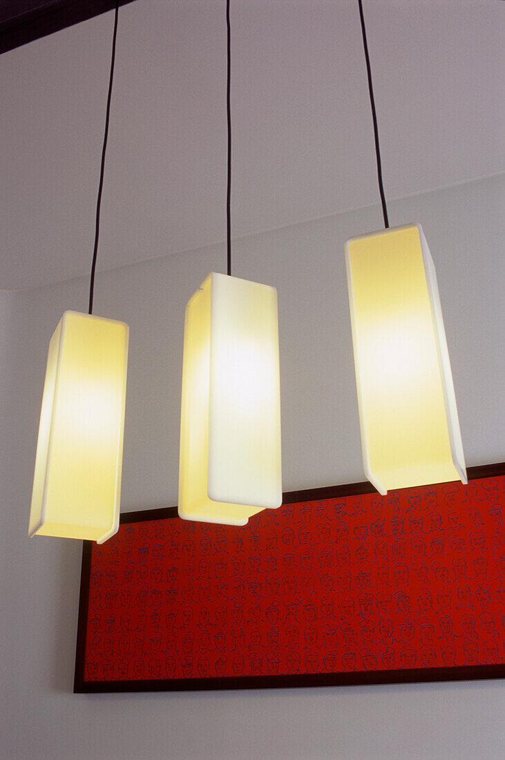 Three rectangular contemporary hanging lights switched on in dining room