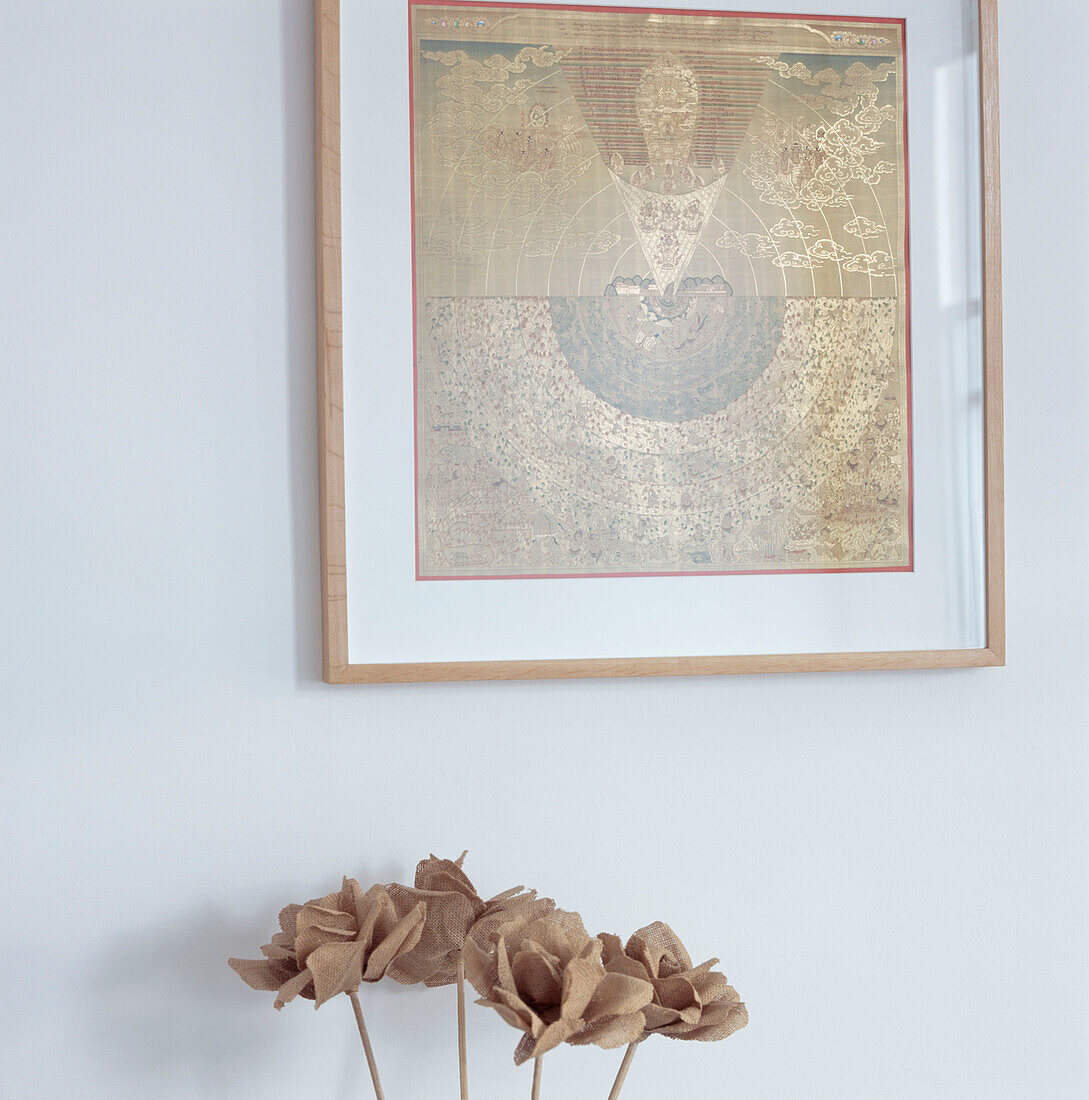Nahaufnahme einer weißen Wand mit gerahmtem orientalischem Golddruck und getrockneten Blumen