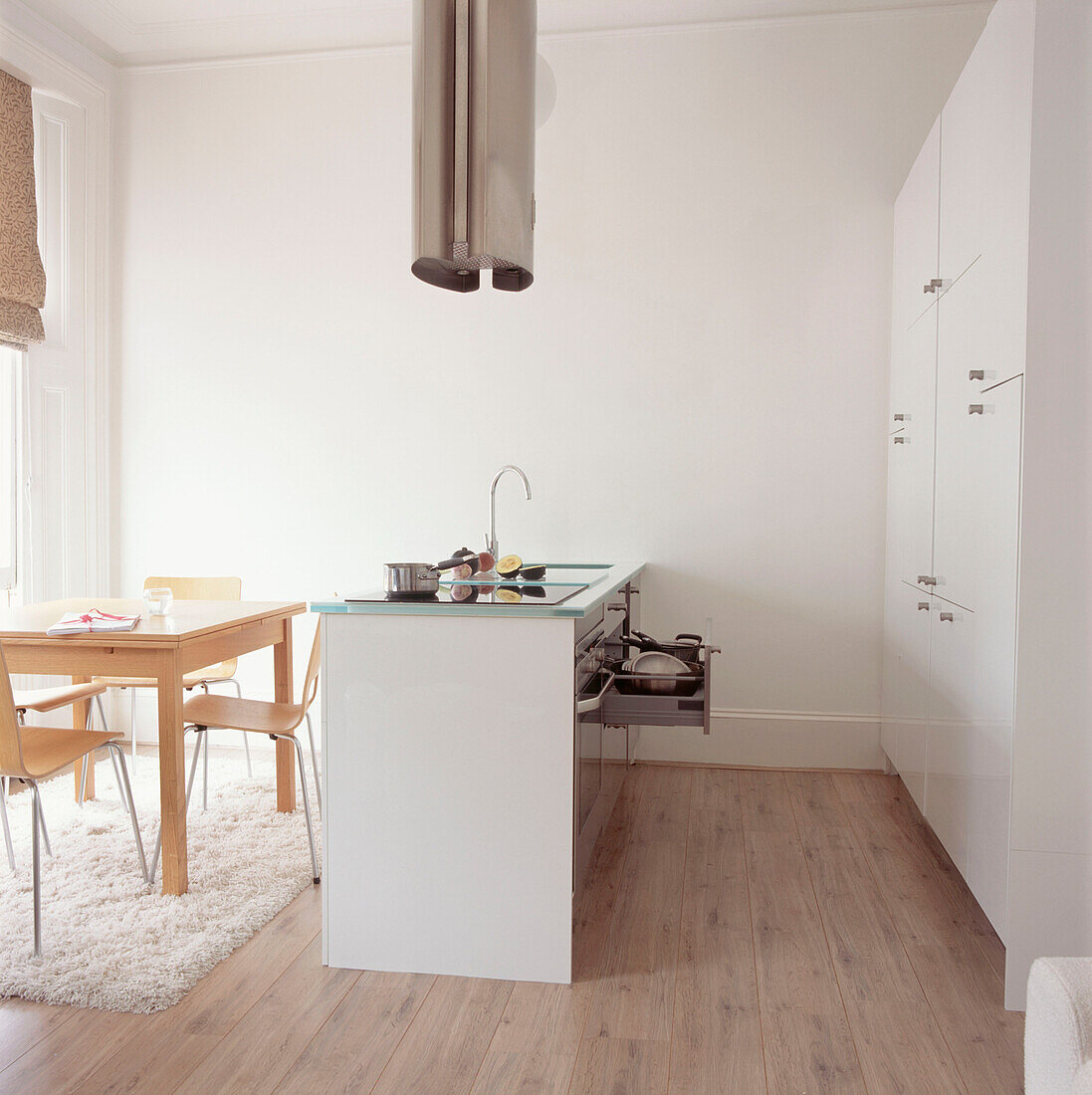Essbereich in der Küche eines Studioapartments mit einer Wand aus weißen Einbauschränken
