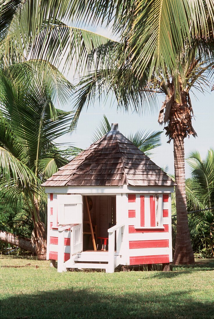 Rot und weiß gestreiftes Spielhaus in einem tropischen Garten