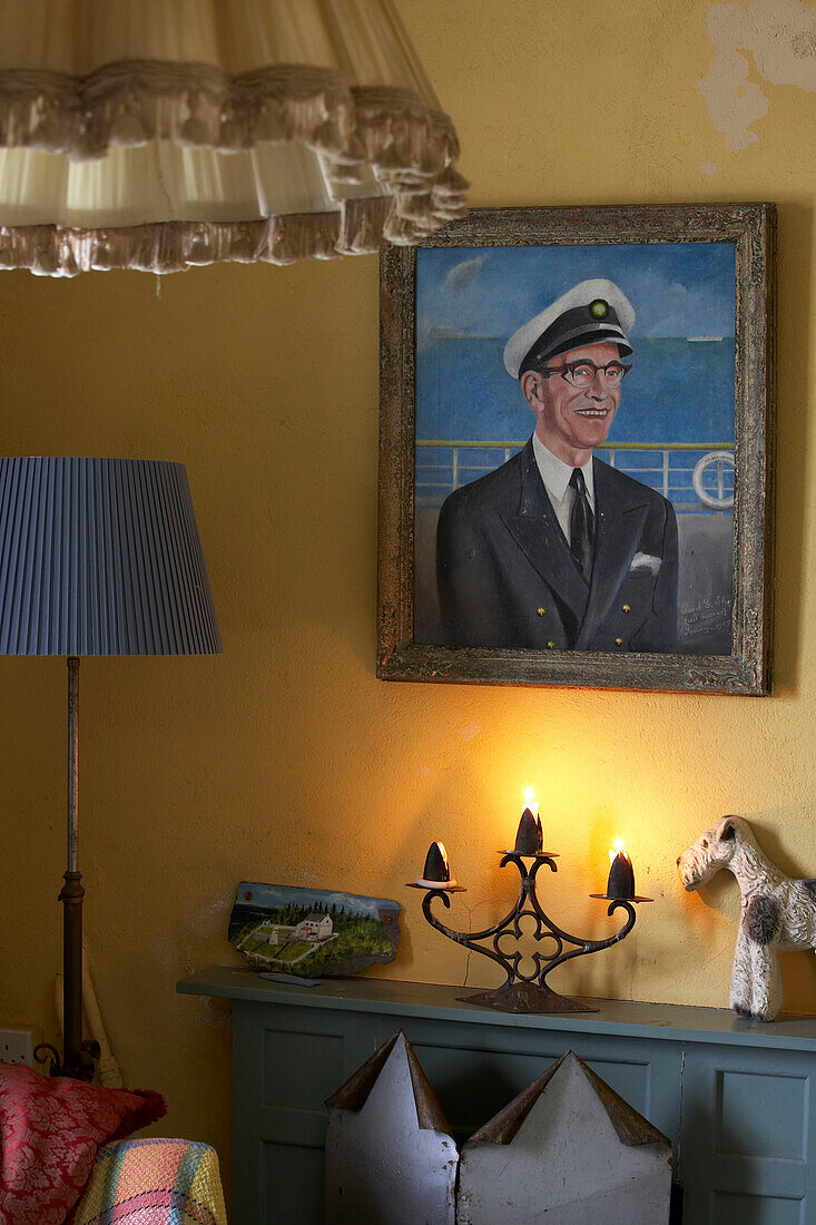 Nahaufnahme eines gelben Wohnzimmers mit dem Porträt eines Seekapitäns, das über dem Kamin hängt