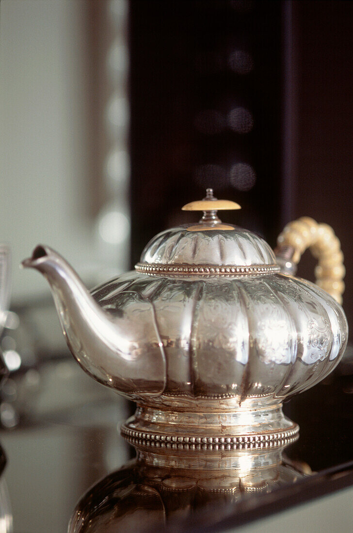 Vintage silver teapot on mirrored table