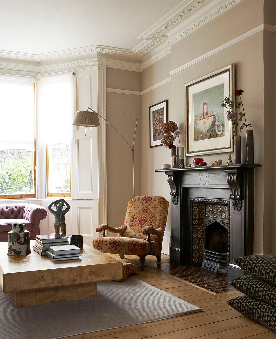 Low wooden coffee table and Victorian fireplace in in London townhouse, UK