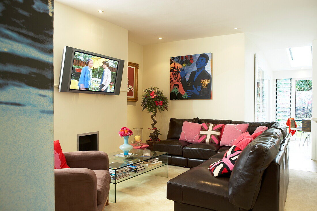 Braunes Ledersofa mit wandmontiertem Fernseher im Wohnzimmer eines flippigen Hauses in London, England, Vereinigtes Königreich
