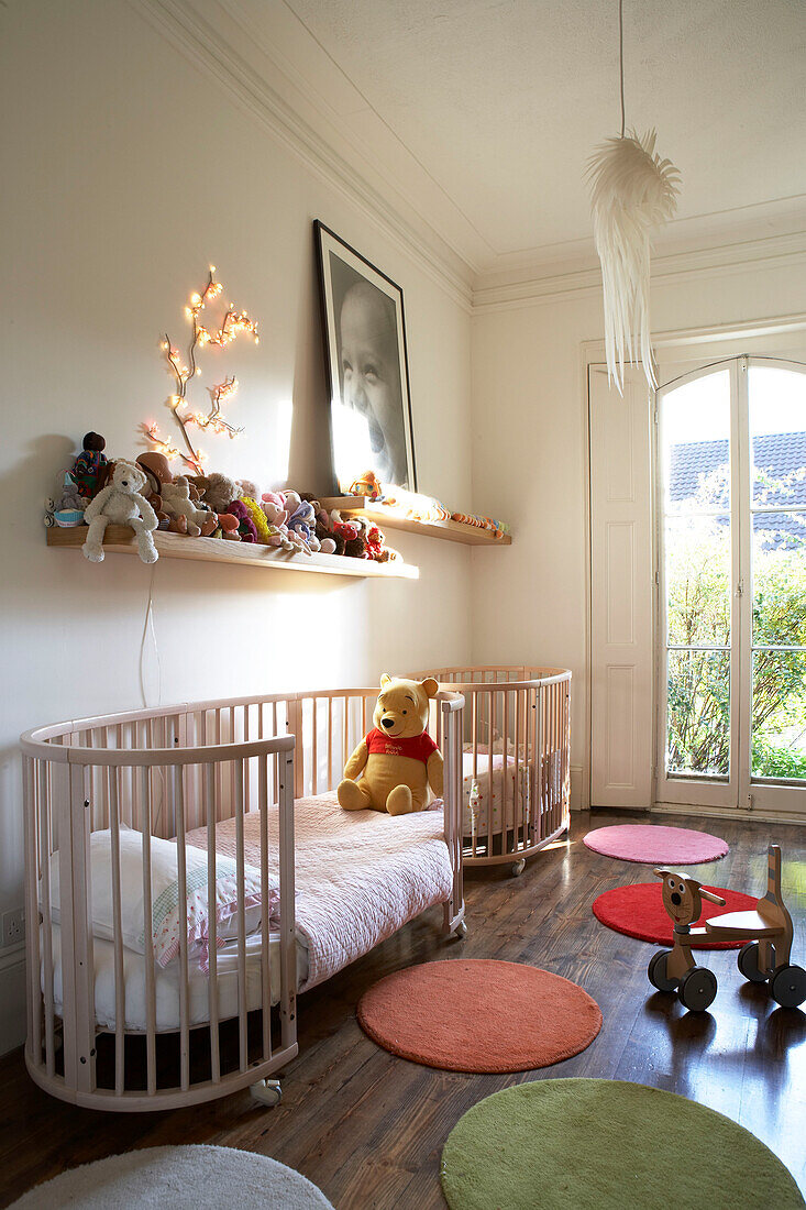 Contemporary Nursery room with colourful circular rugs and a large cot bed