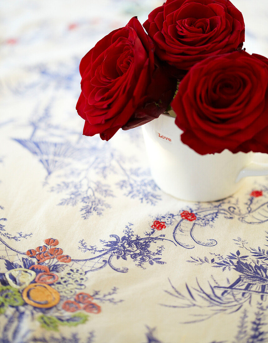 Rote Rosen auf einer bestickten Tischdecke