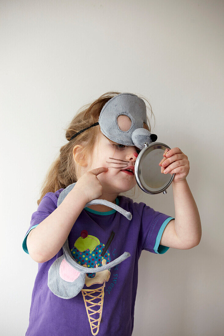 Little girl with purple T-shirt dressing up in a mouse mask