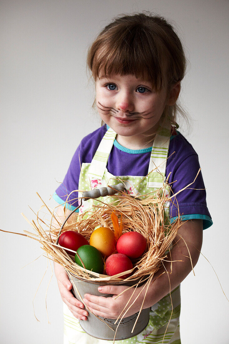 Junges Mädchen mit einem Eimer voller bunter Ostereier