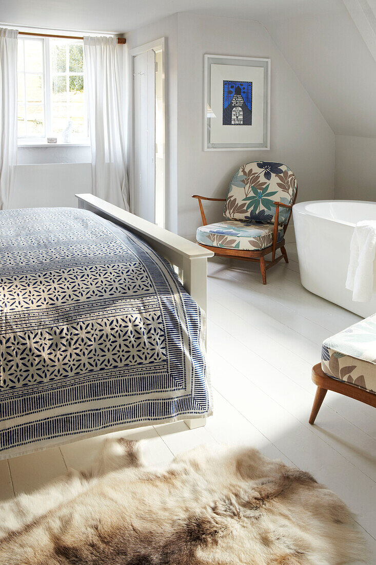 Weiß getünchtes Schlafzimmer im Dachgeschoss mit eigenem Bad mit freistehender Badewanne