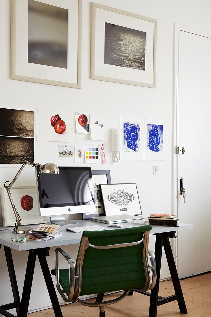 Schreibtisch mit Computer und Kunstwerken an der Wand