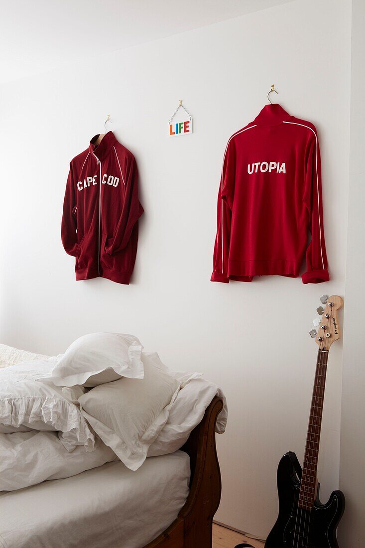 Bedroom detail with red sports shirts hanging on the wall and guitar