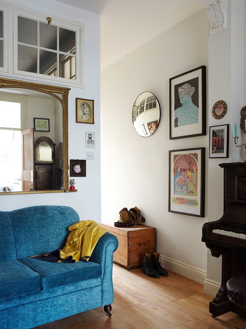 Spiegel mit vergoldetem Rahmen über dem Sofa im Eingangsbereich mit Kunstwerken und Klavier