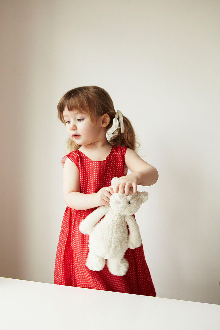 Junges Mädchen in rotem Kleid mit Teddybär