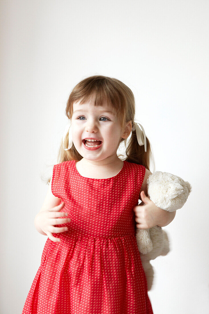 Junges Mädchen in rotem Kleid mit einem Teddybär