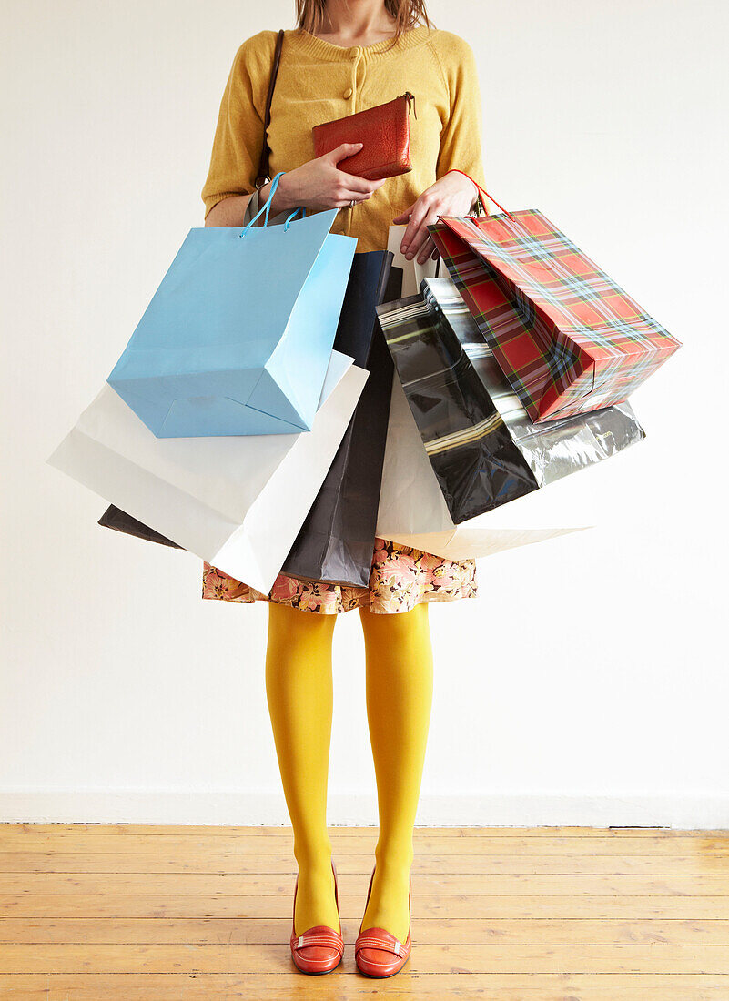 Woman stands holding an assortment of shopping bags