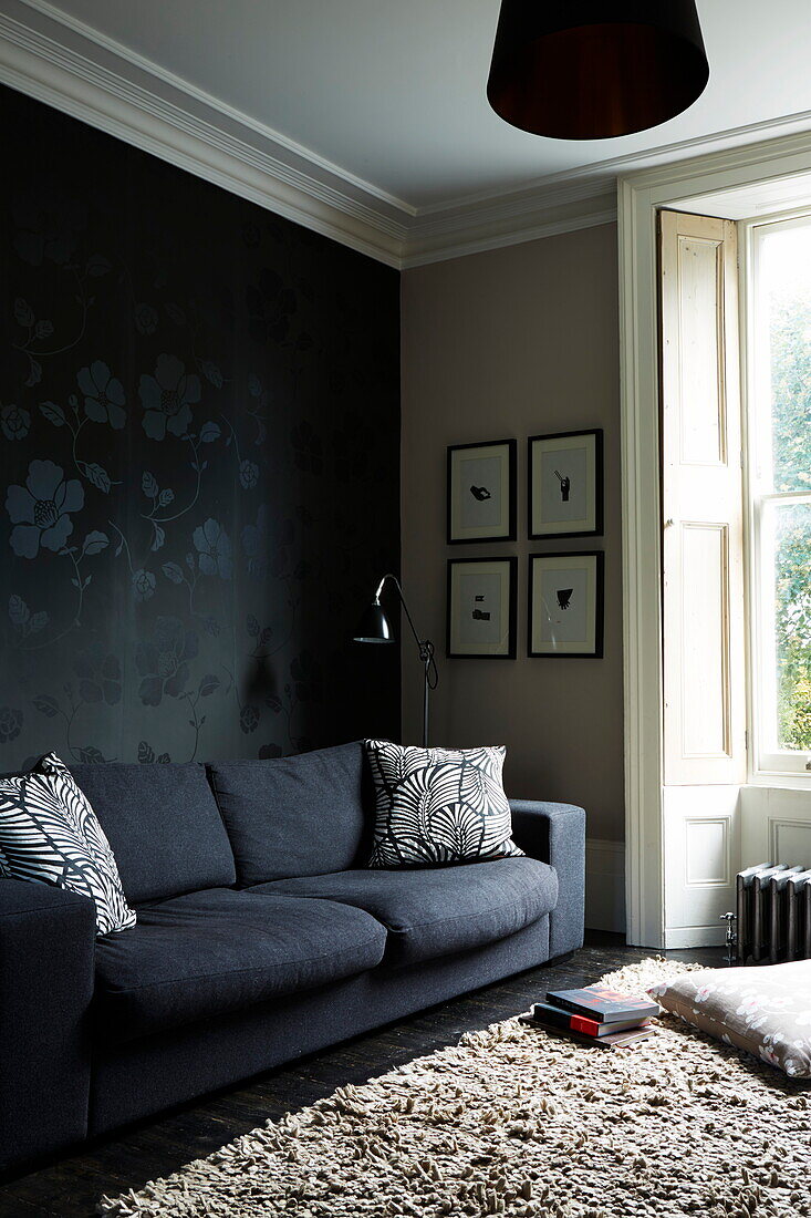 Black sofa with patterned wallpaper in London townhouse, England, UK