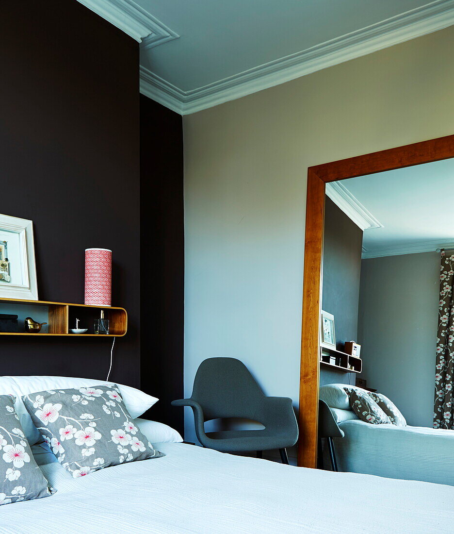 Bedroom with dark feature wall and large wall mirror and armchair