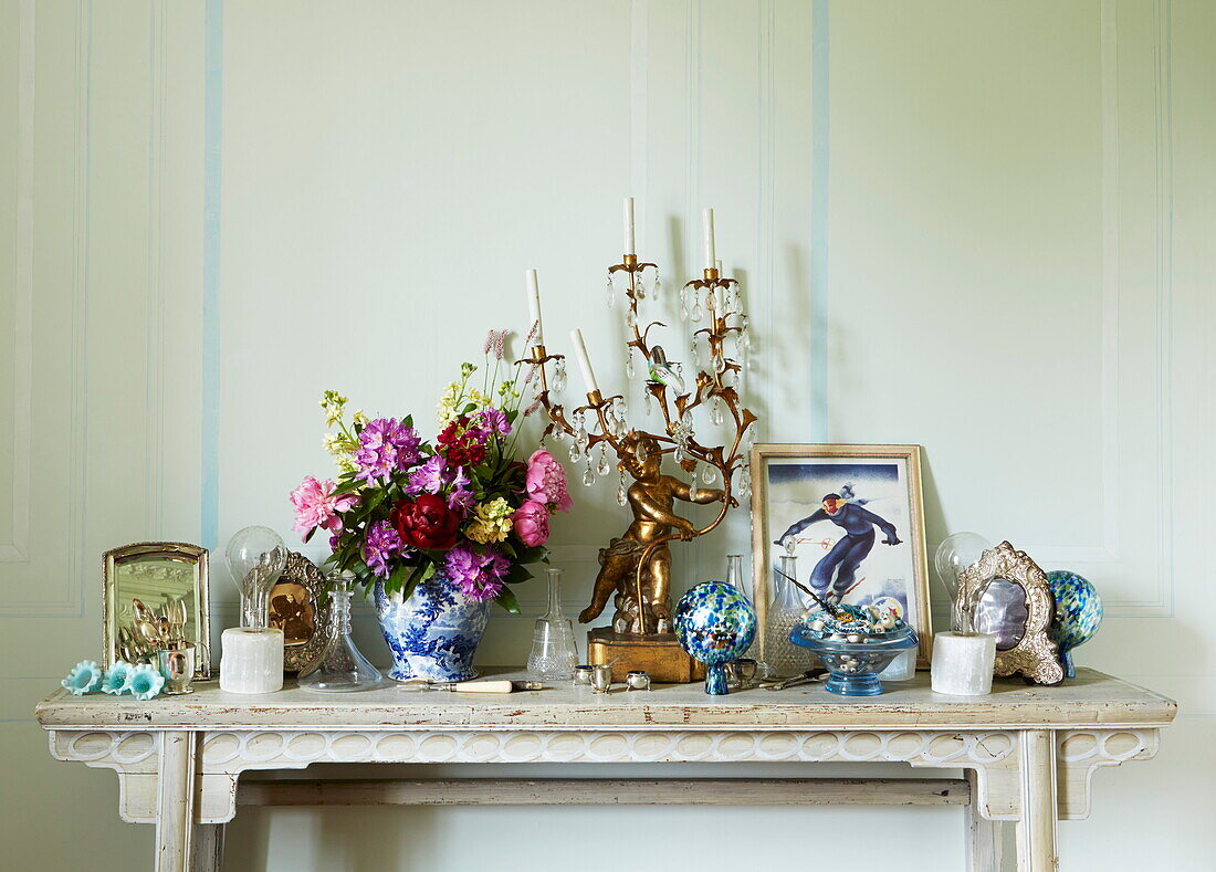 Ornaments and cut flowers on mantlepiece in Cumbria home, England, UK