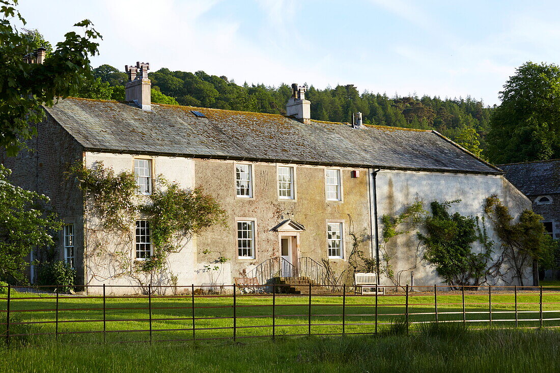 Umzäunter Garten und Steinfassade eines ländlichen Bauernhauses in Cumbria, England, UK