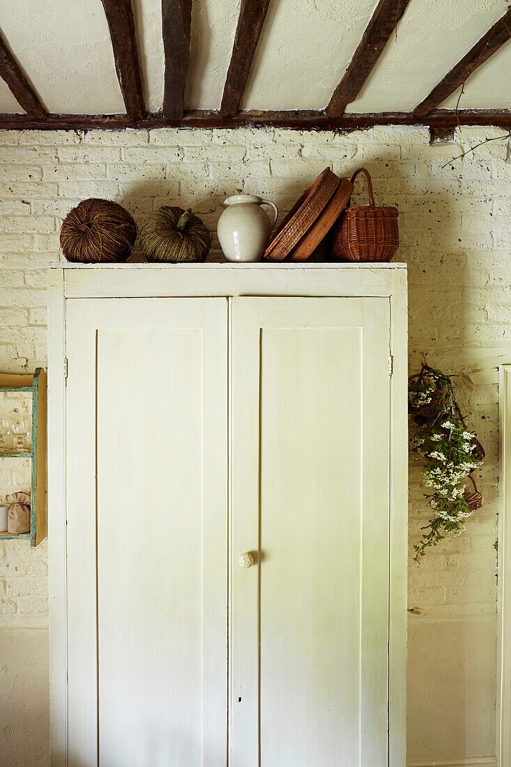 Cream cupboard with baskets in beamed kitchen of Cumbrian home, England, UK