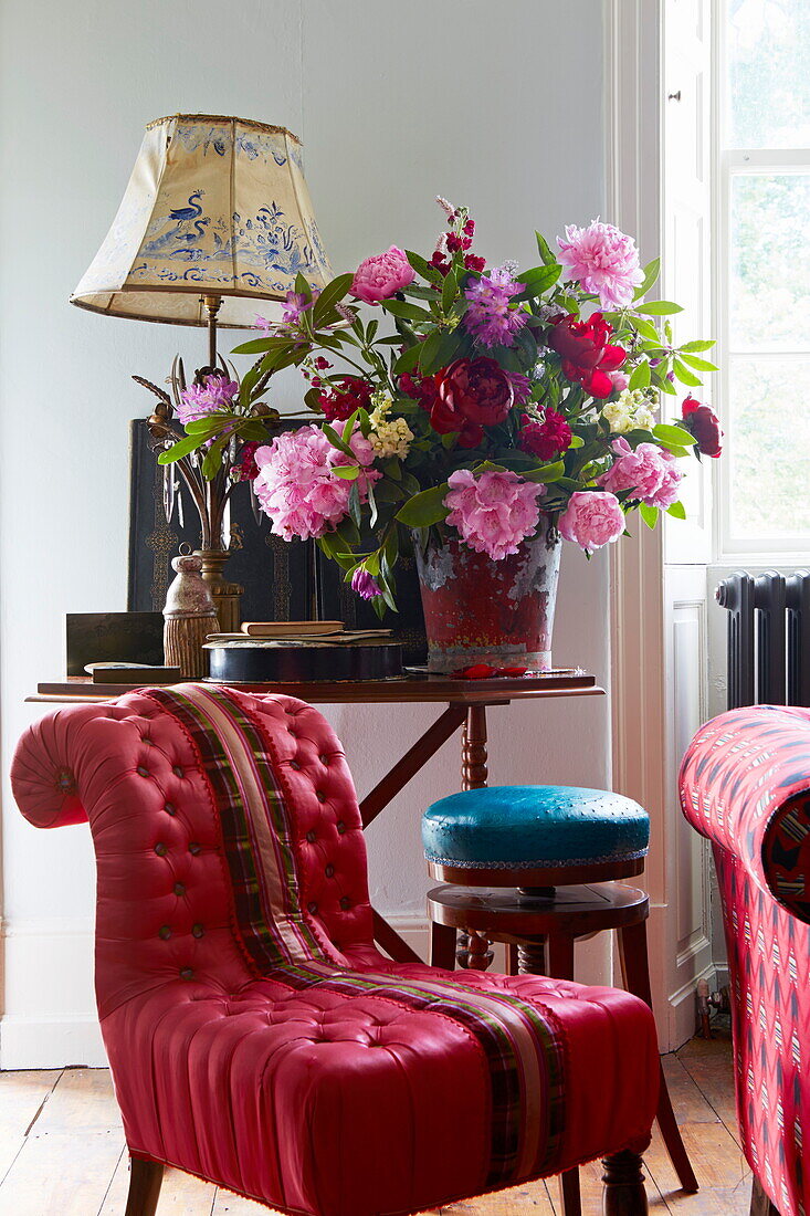 Red upholstered chair with cut flowers on side table in Cumbrian farmhouse, England, UK