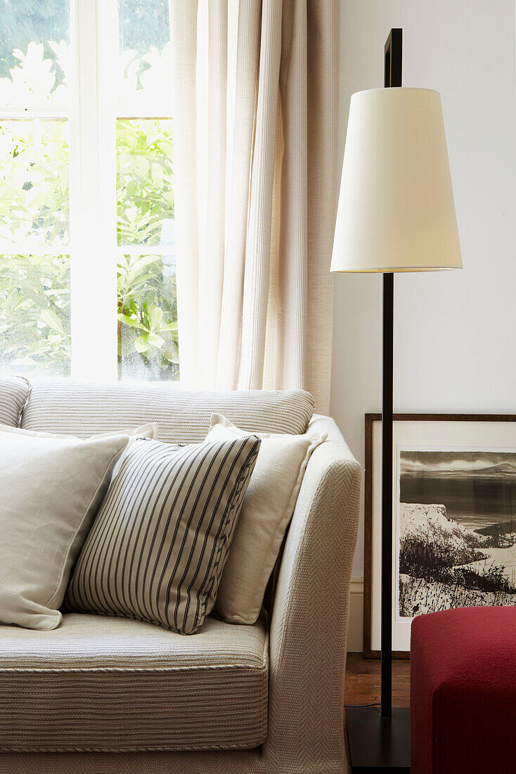 Wohnzimmer mit farblich neutralem Sofa und Kissen mit Leselampe