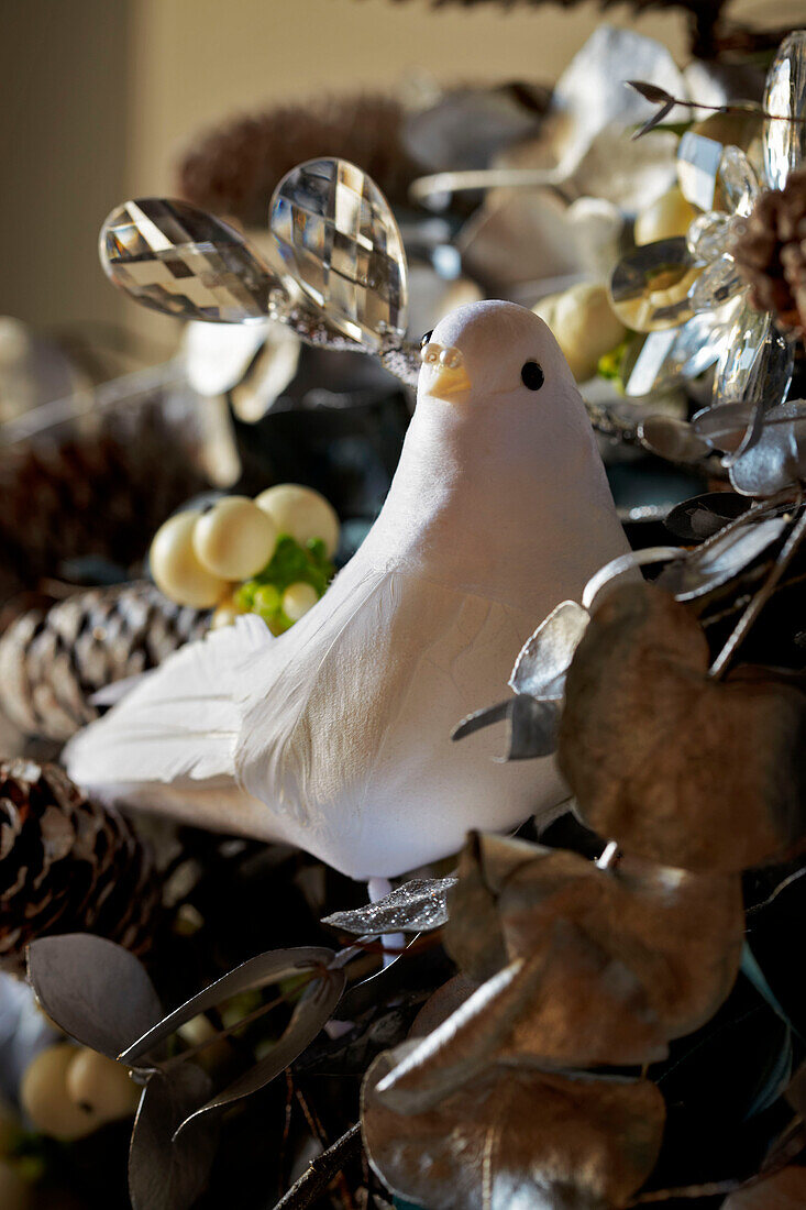 Detail einer weißen Taube in einer festlichen Weihnachtsgirlande, die über einem Kaminsims drapiert ist