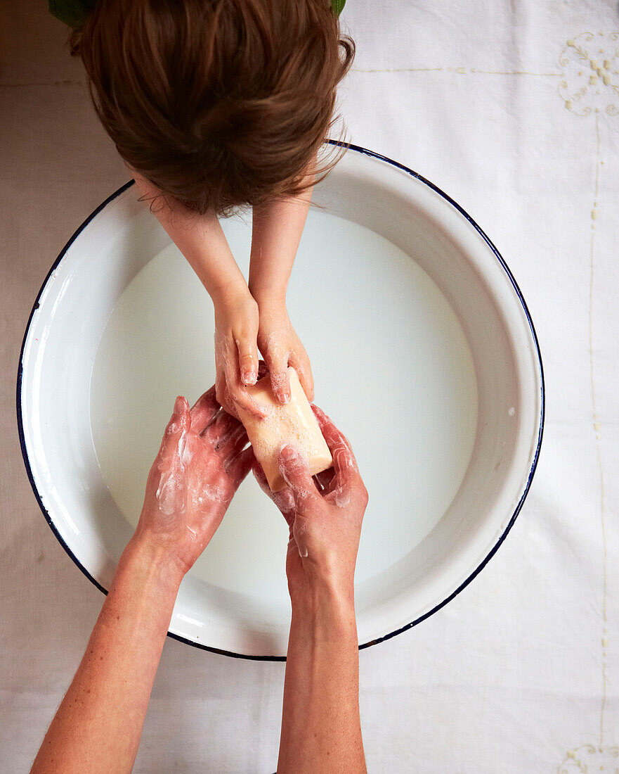 Mother and child washing hands in a bowl