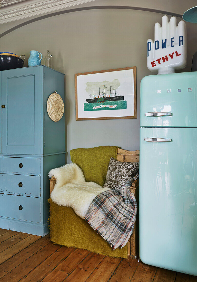 Holzsitzbank mit Fellüberwurf zwischen Kommode und Kühlschrank in Familienküche, Rye, East Sussex, England, UK