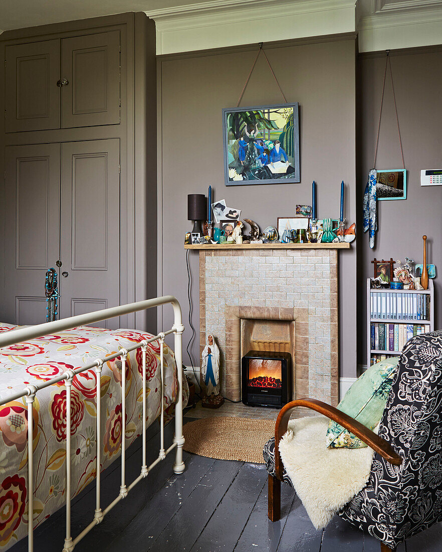 Kachelkamin mit Sessel und Trittbrett im Schlafzimmer eines Familienhauses in Rye, East Sussex, England, UK