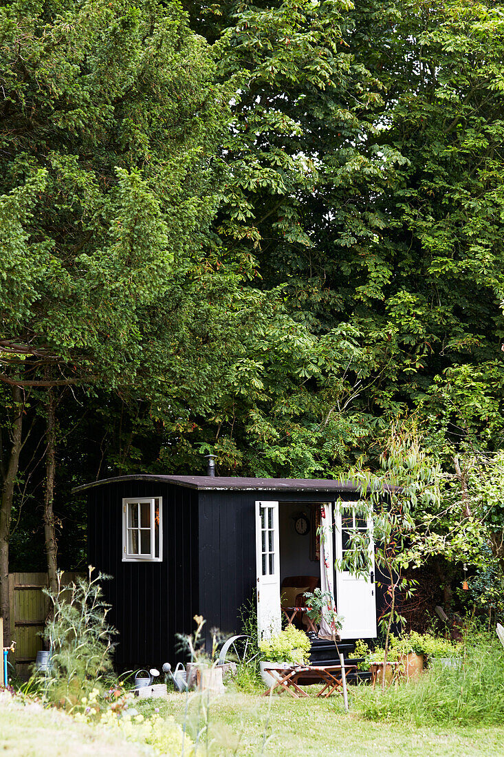 Black painted summerhouse beneath tress in Rye, East Sussex, England, UK