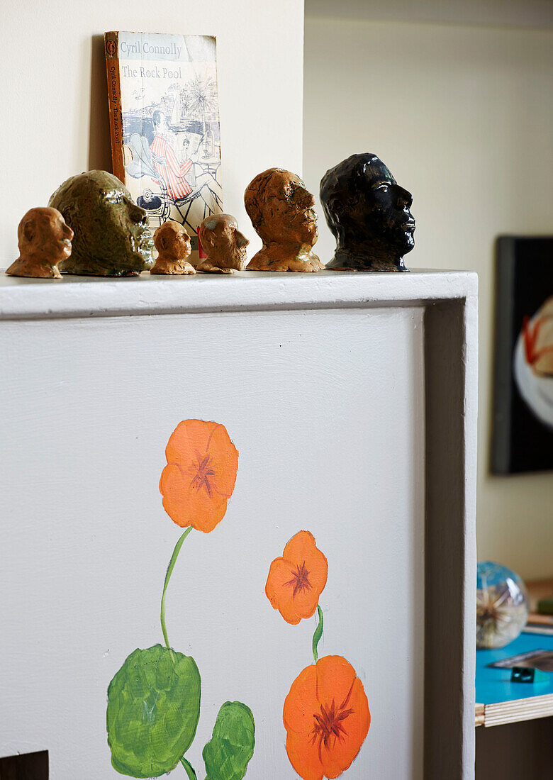 Assorted heads on floral patterned shelf in Hackney home, East London, UK