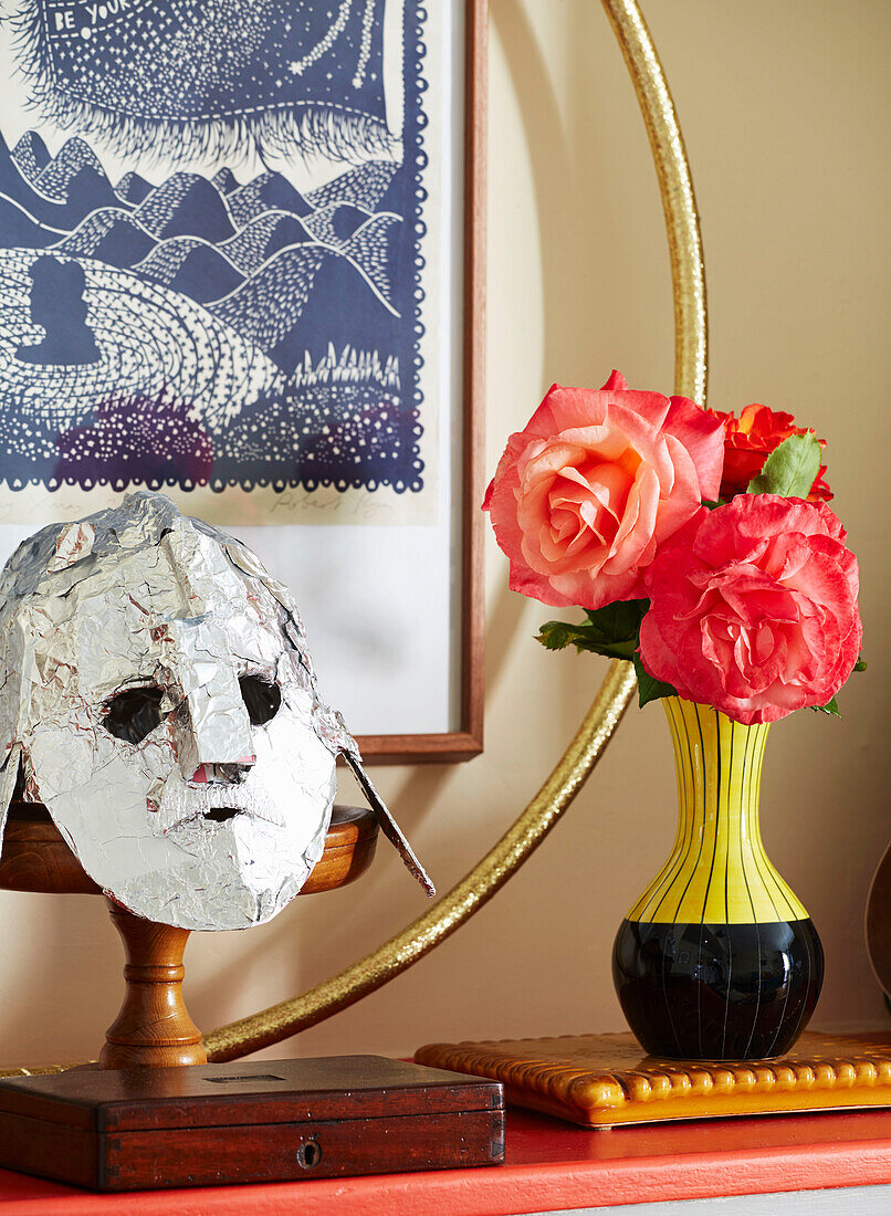 Künstliche Blumen und silberne Maske mit Hula-Hoop-Reifen im Haus einer Familie in Hackney, East London, UK