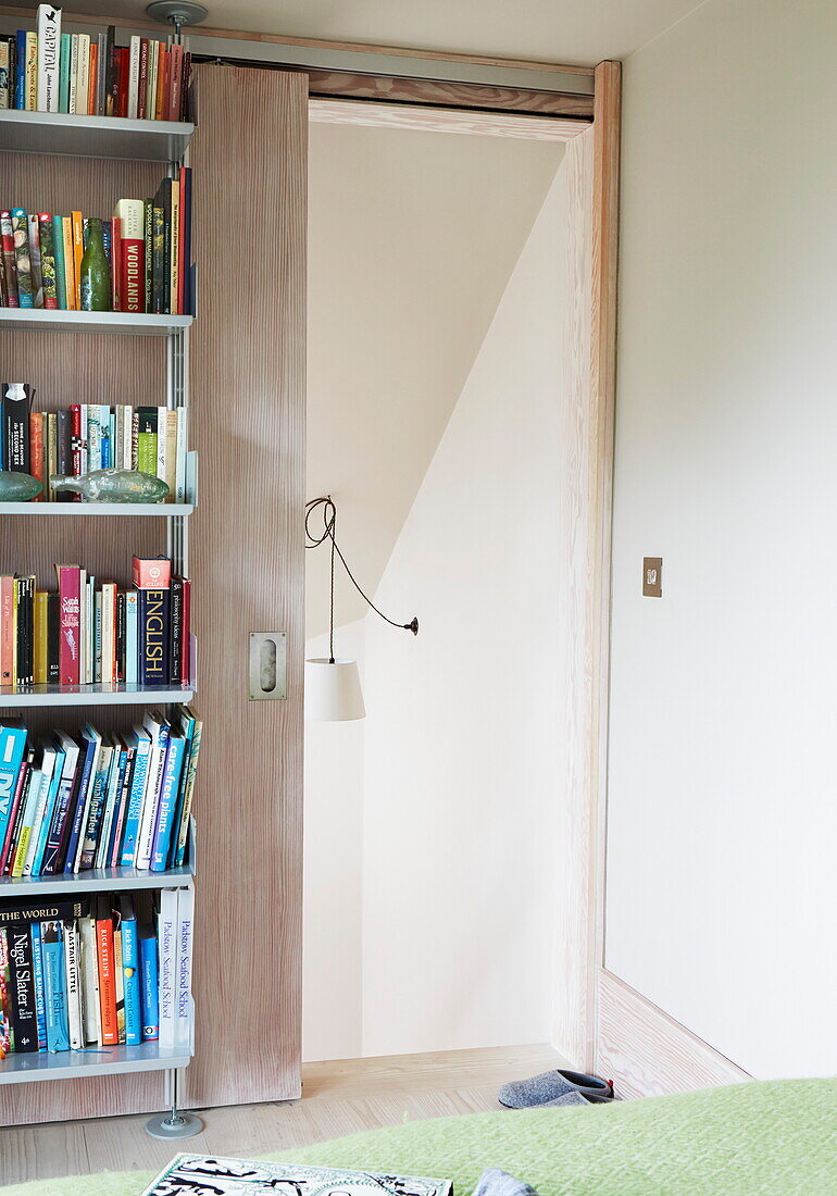 Bücherregal und Schiebetür im Schlafzimmer in einem modernen Haus in London, England, UK