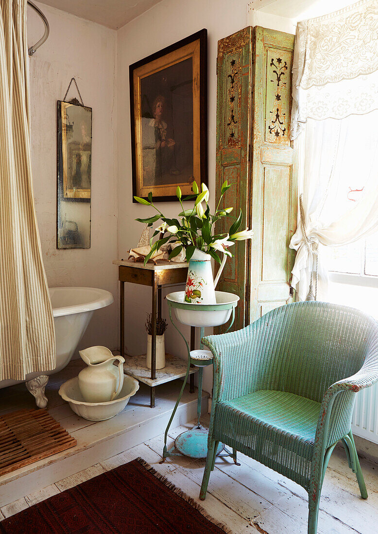 Split level bathroom with cut lilies and painted wicker chair in Evershot home, Dorset, Kent, UK